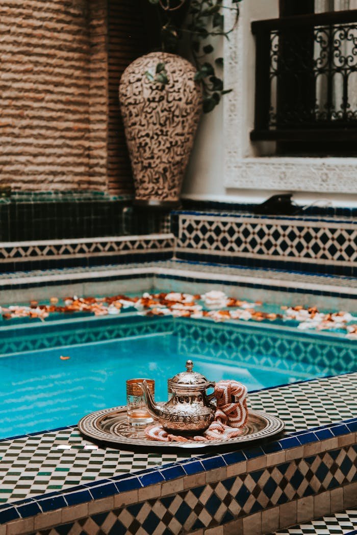 Elegant Moroccan tea setting by a vibrant pool with intricate tile designs in Marrakesh.